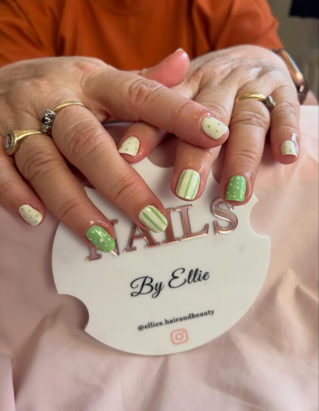 Green and cream gel nails with polka dot and stripe designs